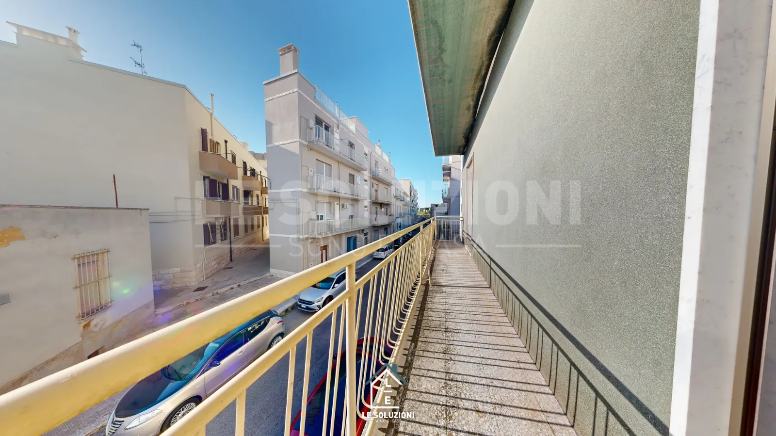 Balcone lungo con ringhiera gialla su strada urbana – Casa indipendente a Putignano